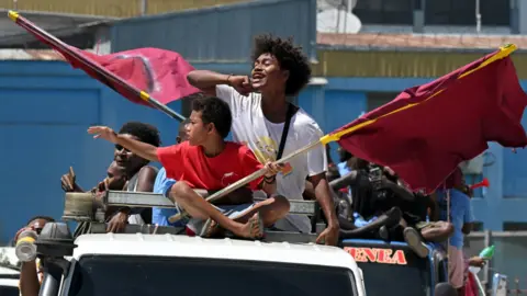 AAP/REUTERS Supporters on a truck wave flags and chant for their political candidate in Honiara on 15 April