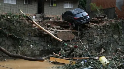 Reuters A car is seen hanging by a swept away street in Petrópolis, Brazil.