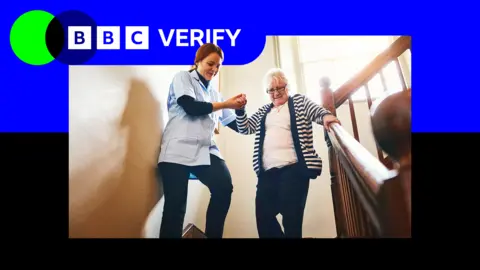 A care worker helps a woman down a flight of stairs