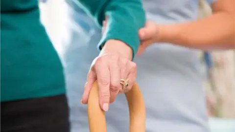 Getty Images Woman helping elderly person