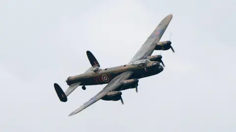 PA Media A dark green military aircraft in the sky