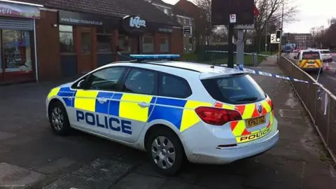 A Northamptonshire Police response car on Barrack Road outside the Lazeez Indian Restaurant in the aftermath of Mr Casey's killing. Police tape is shown to be protecting the scene.