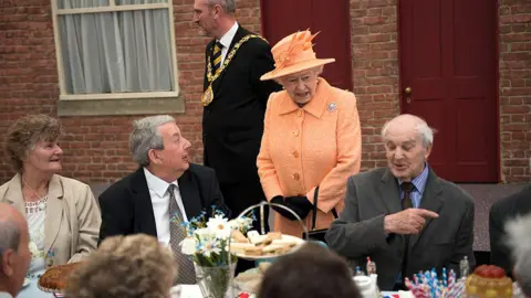 Getty Images The Queen speaks to people sat at a table for a Jubilee street party in 2012