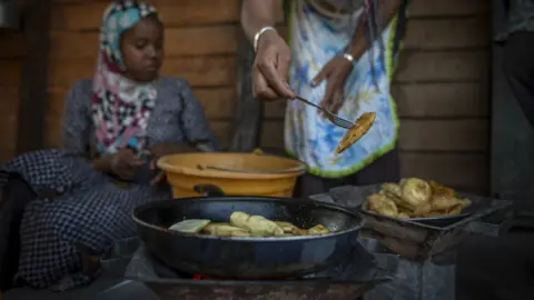 BBC/Shiraaz Mohamed A woman prepares Malagasy Samboza, small triangular pastries filled with beef or vegetables