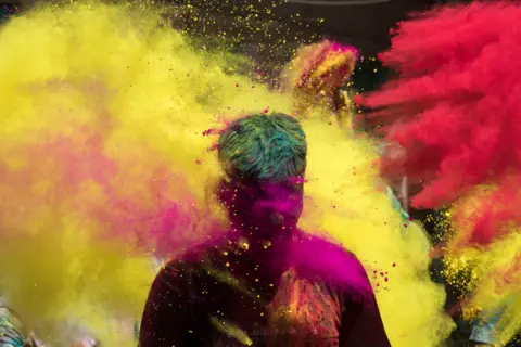 Xavier Galiana / AFP People throw coloured powder as they celebrate Holi, in Jodhpur, India, on 29 March 2021