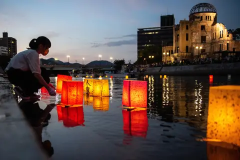 Philip Fong / AFP People release paper lanterns on the Motoyasu River beside the Hiroshima Prefectural Industrial Promotion Hall, commonly known as the atomic bomb dome, to mark the 77th anniversary of the world's first atomic bomb attack in Hiroshima on 6 caugust 2022