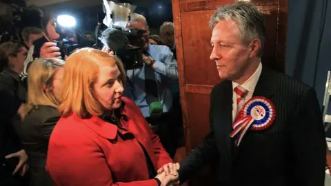 PETER MUHLY/AFP via Getty Images Then-first minister Peter Robinson shakes hands with Naomi Long after losing his east Belfast seat to her in 2010