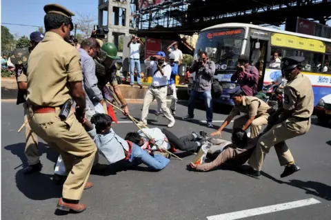 Getty Images Police try to detain students protesting against the California-based Tri-Valley University outside the US consulate in Hyderabad city in 2011.