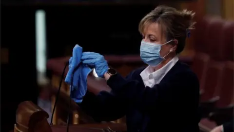 EPA A worker cleans the platform after the speech of each MP during the plenary session at the Lower Chamber of Spanish Parliament, in Madrid, Spain, 22 April 2020