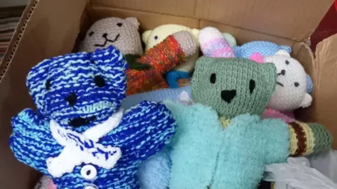 PA Media About a dozen bears in various colours and designs placed in a cardboard box
