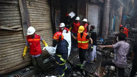Reuters Volunteers recover a dead body from a burnt warehouse in Dhaka