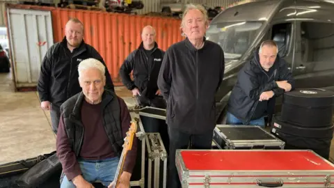 Leigh Milner/BBC Dr Feelgood stand with their equipment and police officers