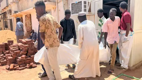 Ken Mungai/Five men outside the morgue of BBC Omdurman carry their bodies in white sheets 