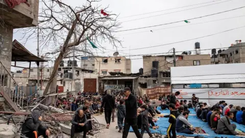 EPA Displaced Palestinians perform the third Friday prayer of the holy month of Ramadan next to the ruins of a mosque destroyed earlier by an Israeli raid in Rafah, southern Gaza Strip, 29 March 2024.