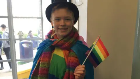 Alastair France Danny France wearing a rainbow scarf and holding a Pride flag
