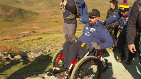 Martin Hibbert using a specially adapted wheelchair to climb a slope in the UK