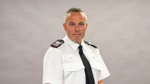 Northamptonshire Fire and Rescue Service Man with short hair wearing a fire officer's uniform against a neutral background