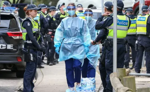 Getty Images A queue of police guard a path for health care workers to walk through to the housing towers