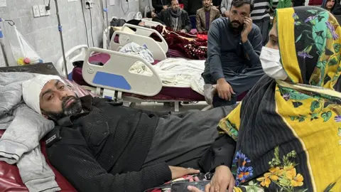 A man, still wearing his police uniform, receiving treatment in hospital in Peshawar