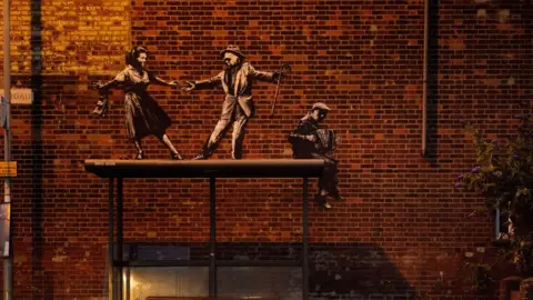 Banksy art of people dancing on a bus-stop