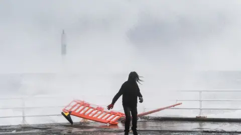 Keith Morris A person runs away from high waves in Aberystwyth