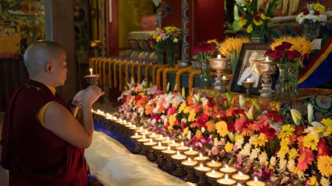 EPA-EFE/REX/Shutterstock A Buddhist monk lights candles for butter lamps during a prayer session to mark the State Funeral of Queen Elizabeth II at Ka-Nying Shedrub Ling Monastery in Kathmandu, Nepal