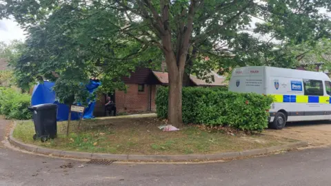 A police van and tent outside a house