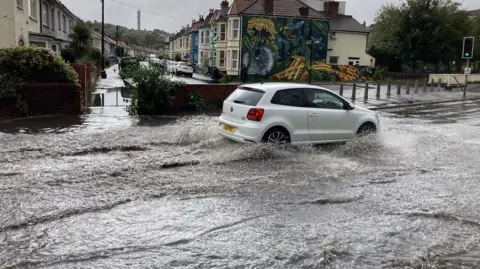 A white car drives through floodwater 