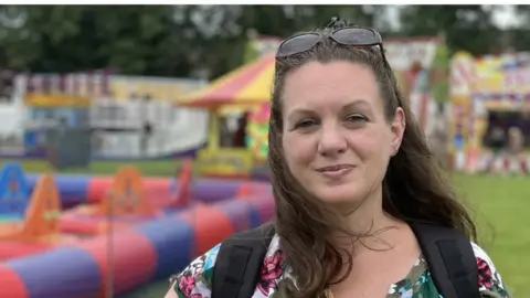 Sam Read/BBC Woman with brown hair and sunglasses in a field at the Northampton Balloon Festival