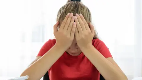 Getty Images A girl holds her head