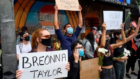 Getty Images Black Lives Matter protesters hold up signs as they commemorate Breonna Taylor on what would have been her 27th birthday in Hollywood, California