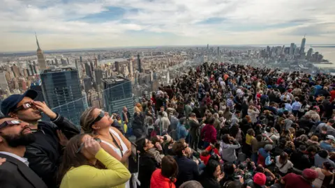 Getty Images Hundreds watch the sky on the viewing platform of the Edge in New York