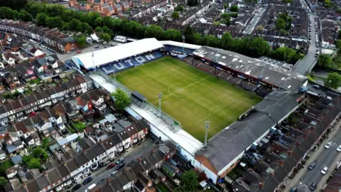 Ronald Grant An aerial view of Luton Town's Kenilworth Road stadium. The green grass from the football pitch is visible as well as the four stands which are surrounded by rows of terraced housing.