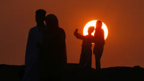 Amr Abdallah Dalsh/Reuters People taking selfies as the sun rises in Abu Sir, Egypt - Wednesday 10 April 2024