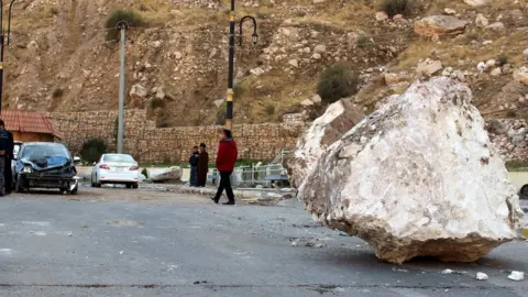 EPA An Iraqi Kurdish man walks by a large rock which fell from the top of a mountain during the earthquake that hit Darbandikhan town