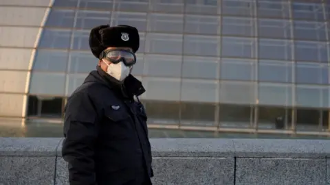 Reuters A security guard wears a mask in Beijing