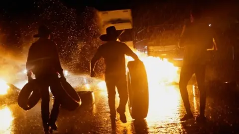 Reuters Bolsonaro supporters move tyres to a burning barricade near Abadiania, central Brazil. Photo: 31 October 2022