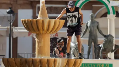 Reuters Men cooling off in a fountain in Ronda, Spain, 10 July 2022