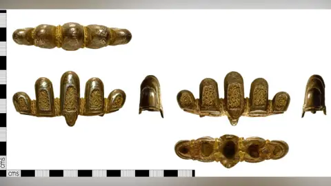 The Portable Antiquities Scheme Five views of a Viking-era sword pommel. It is made up of five lobes, which decrease in width from the tallest on in the middle. Each of the lobes has an inset panel of with an interlocking pattern of gold wire on a gold panel. More gold wire is woven between the lobes. On the left edge and on the lower edge is a black and white measure in cms.