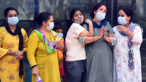 Hindustan Times/Getty Images Relatives and family members of a person who died of Covid-19, break down during the cremation