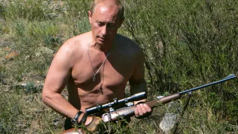 AFP Vladimir Putin with a hunting rifle, pictured in 2007. The image is the July page on the 2018 Putin calendar.