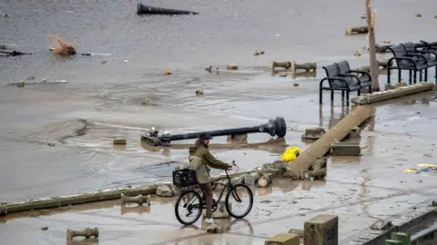 EPA A man bikes through debris from flooding.