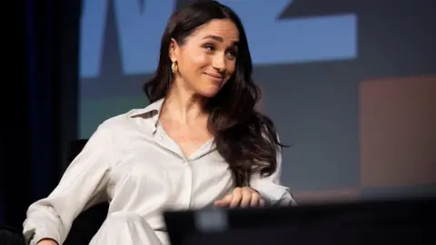 Reuters Meghan in silky white shirt, looking over