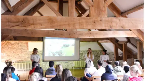 Action for Conservation Young people in a hall giving a presentation