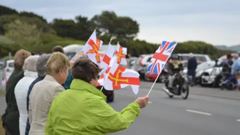 BBC People waving Guernsey flags watching the Cavalcade