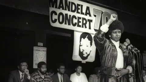 Reuters Winnie Mandela raises her fist in a black power salute after announcing that a massive pop concert will be held to mark the 70th birthday of her husband in 1988