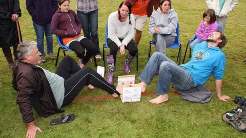 World Alternative Games Two men wrestle toe-to-toe as one competitor arches his back with a pained expression
