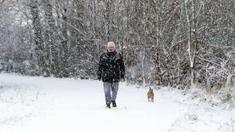 PA Media A man walks his dog in the snow in Gateshead, back in December