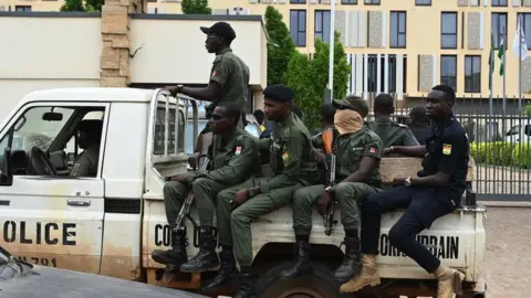 Getty Images A police officer ride on the back of a pick-up truck as they patrol in Niamey on 21 August, 2023.