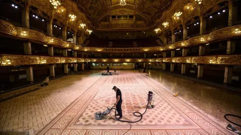 PA Media Henry Armitage, a wood sanding technician, working to restore the floor of the historic Blackpool Tower Ballroom